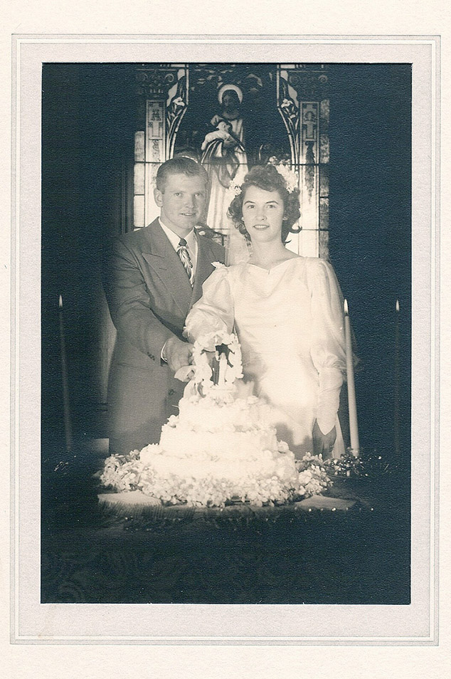 An old black and white wedding portrait of a bride and groom cutting their cake