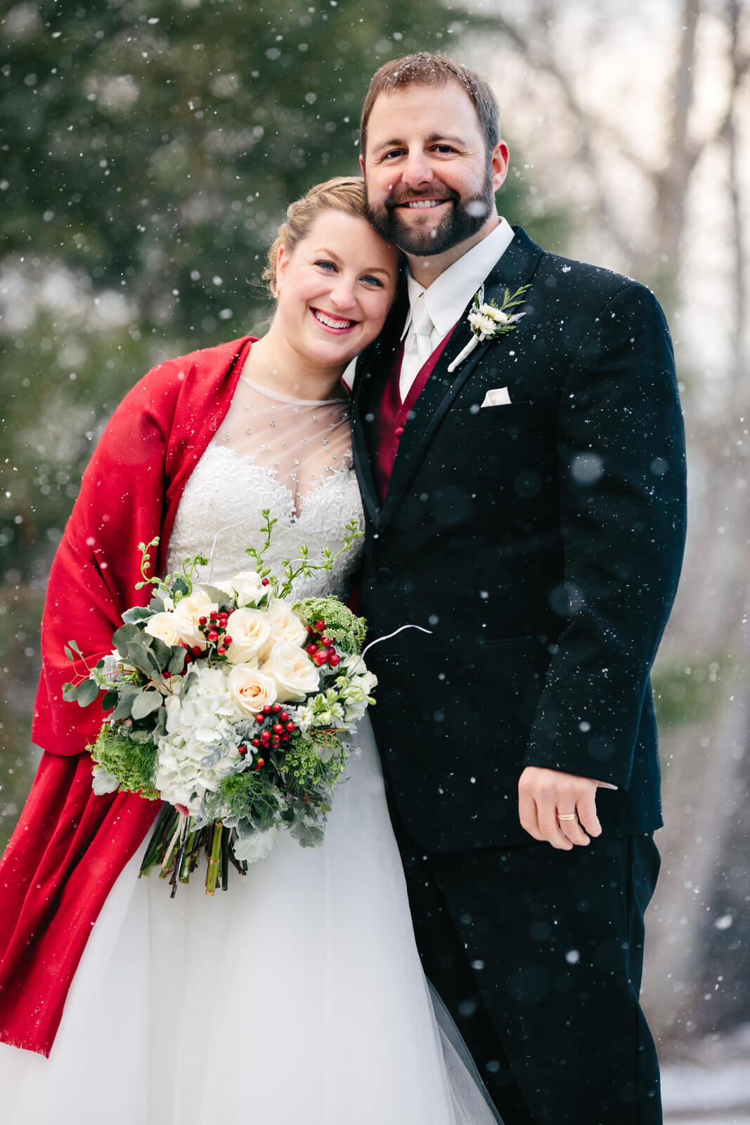 A bride and groom smile as snowflakes fall during their winter wedding in Missoula Montana