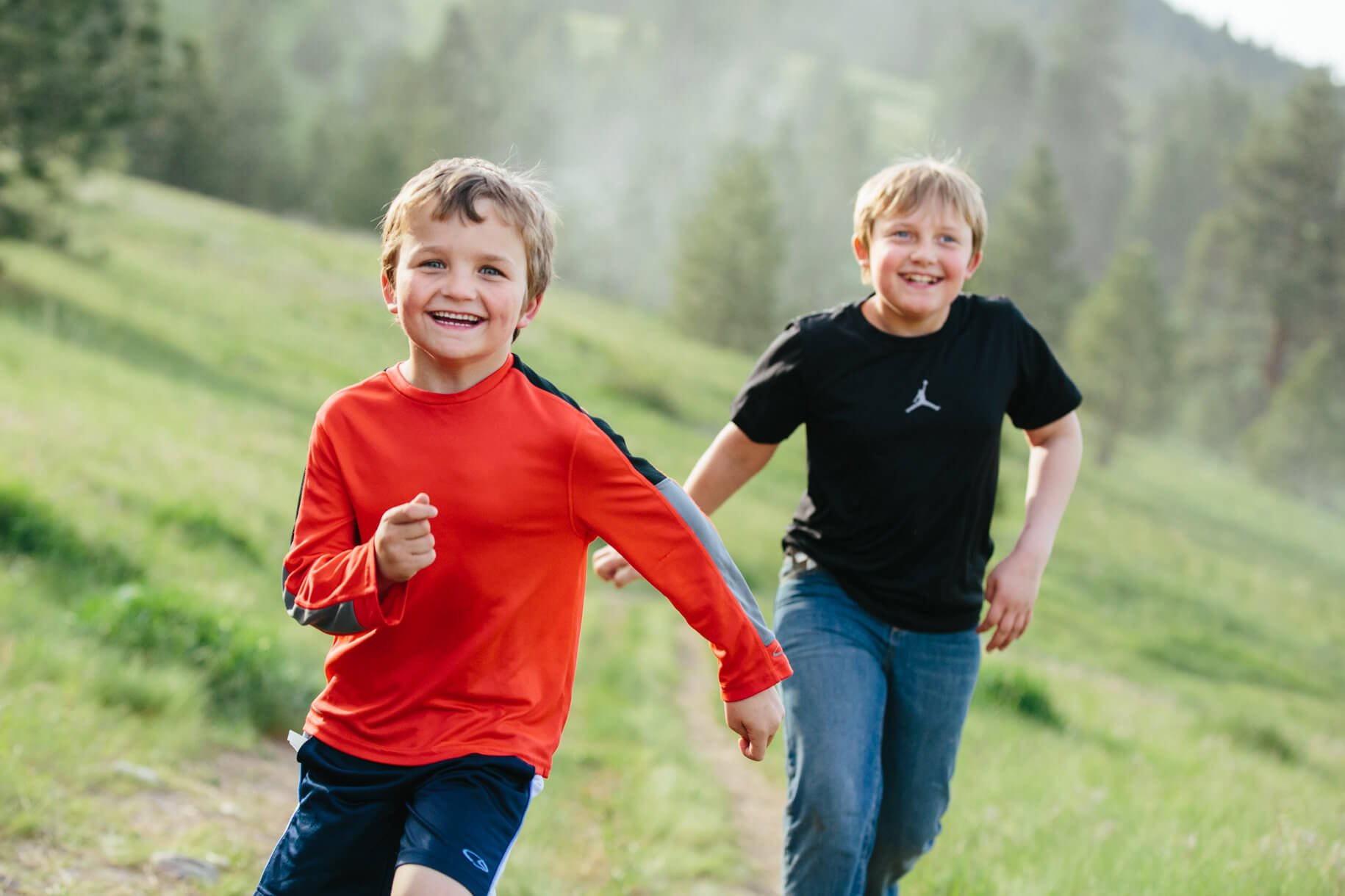 Two brothers run on a dirt trail during their family session in Missoula Montana