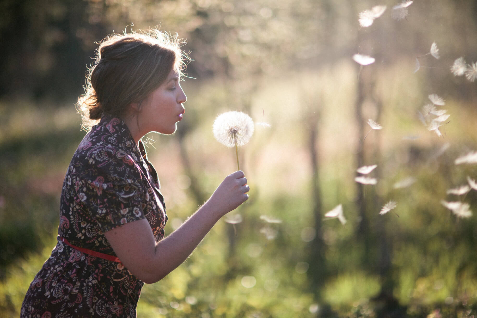 A woman blows dandelion fluff off a flower during her portrait session in Greenough Montana