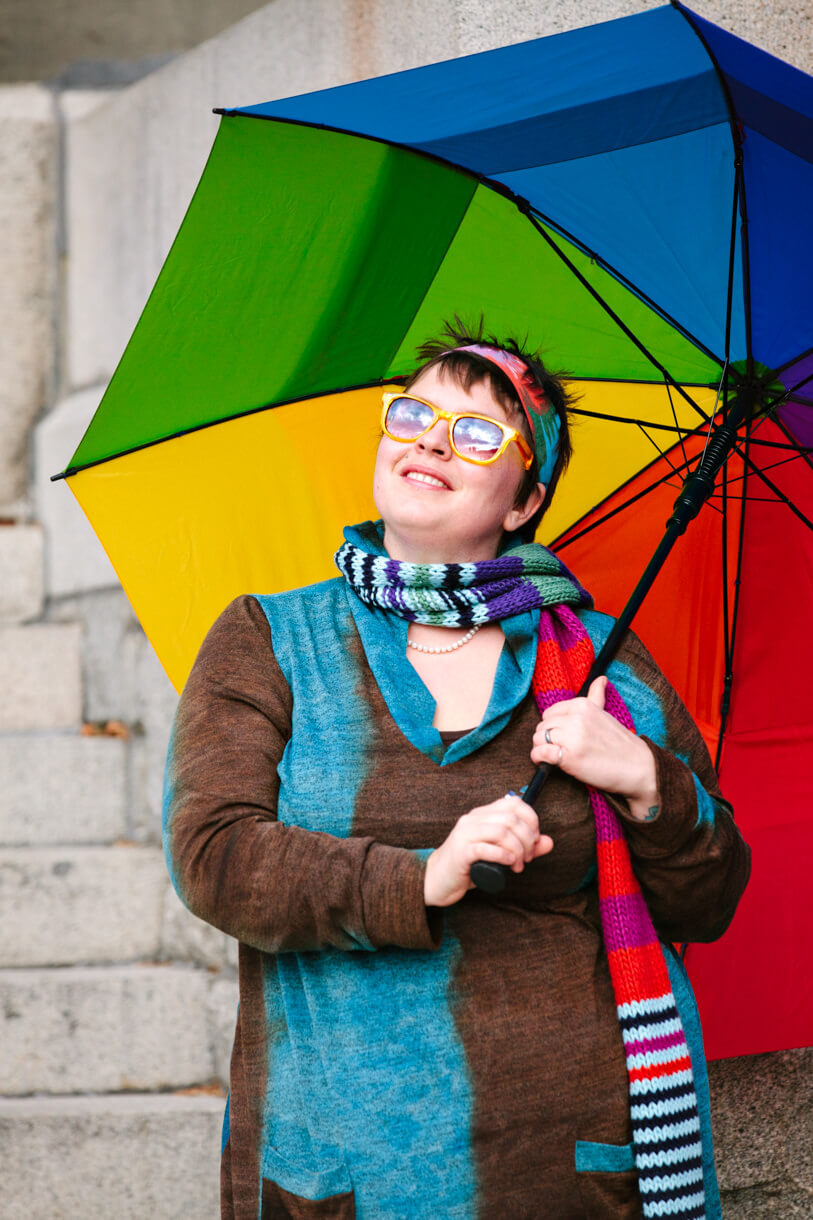 A woman holds a rainbow colored umbrella during her portrait session in Missoula Montana