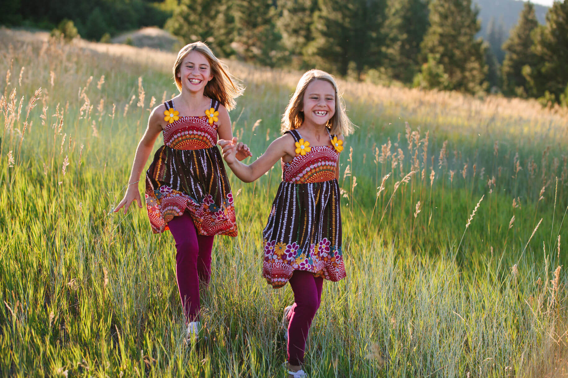 Two sisters run through tall grass during their family session in Missoula Montana