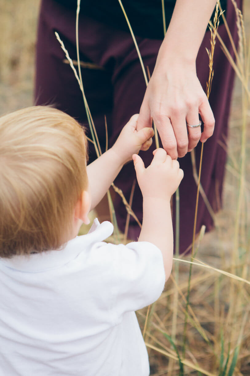 A toddler grasps his mother's finger during their family portraits in Missoula Montana