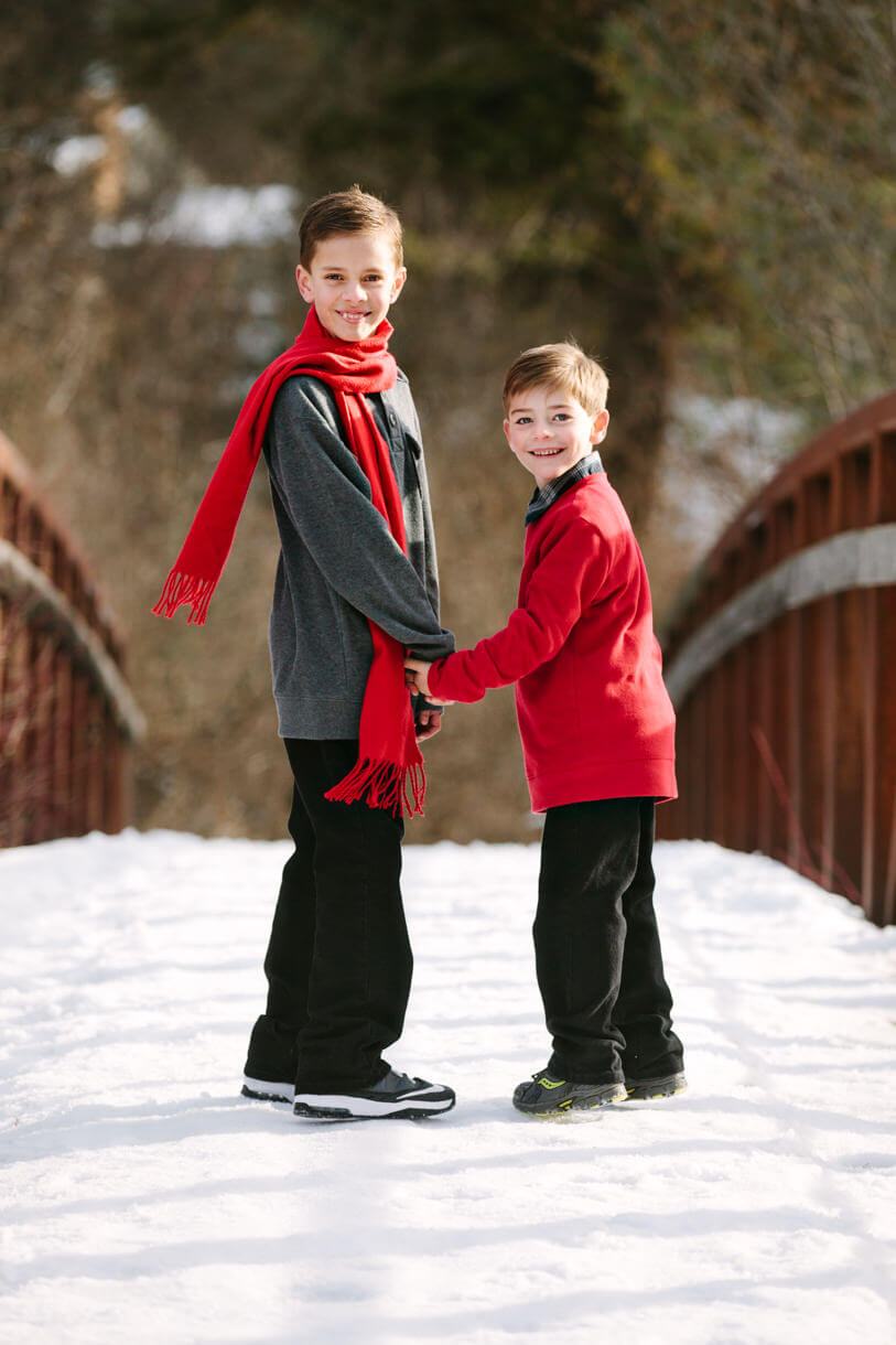 Two brothers cross a snow covered bridge during their family photos in Missoula Montana
