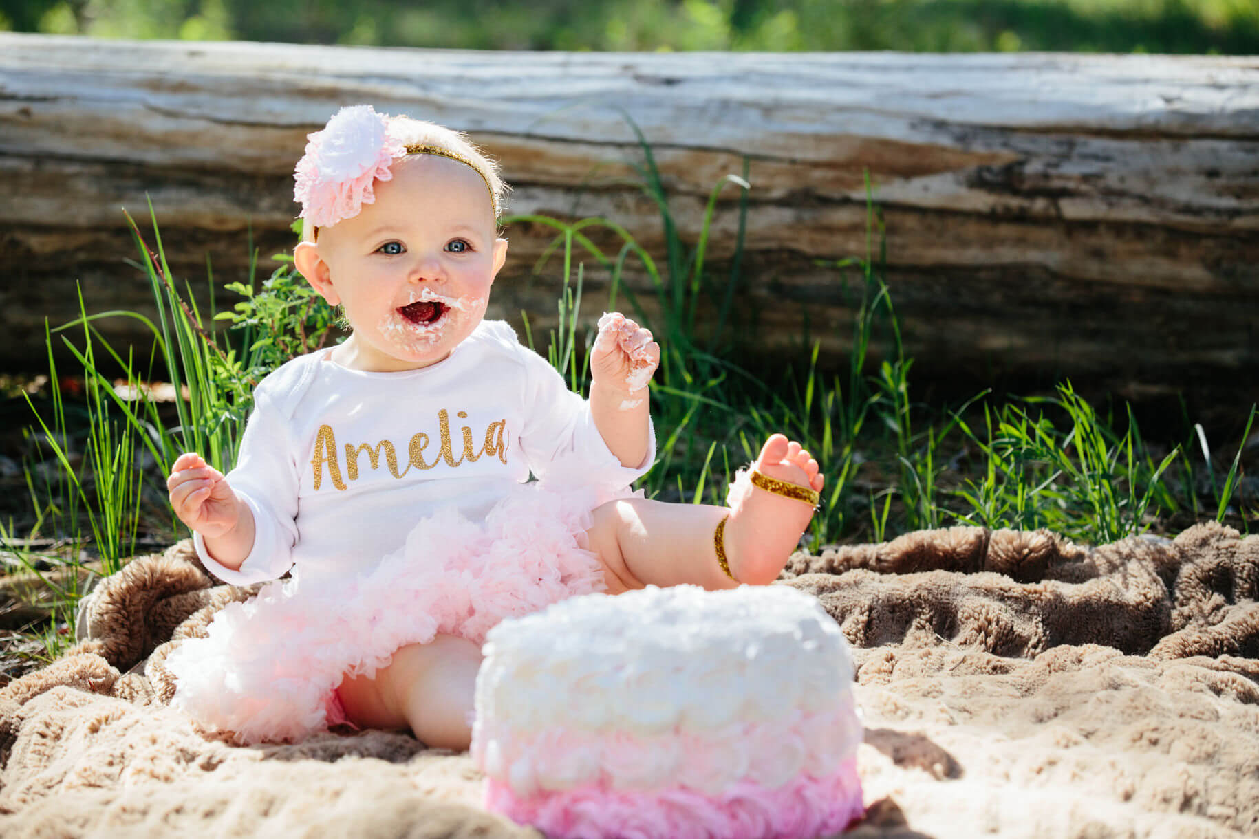 A one year old girl laughs and smiles as she smashes her birthday cake on her first birthday in Lolo Montana
