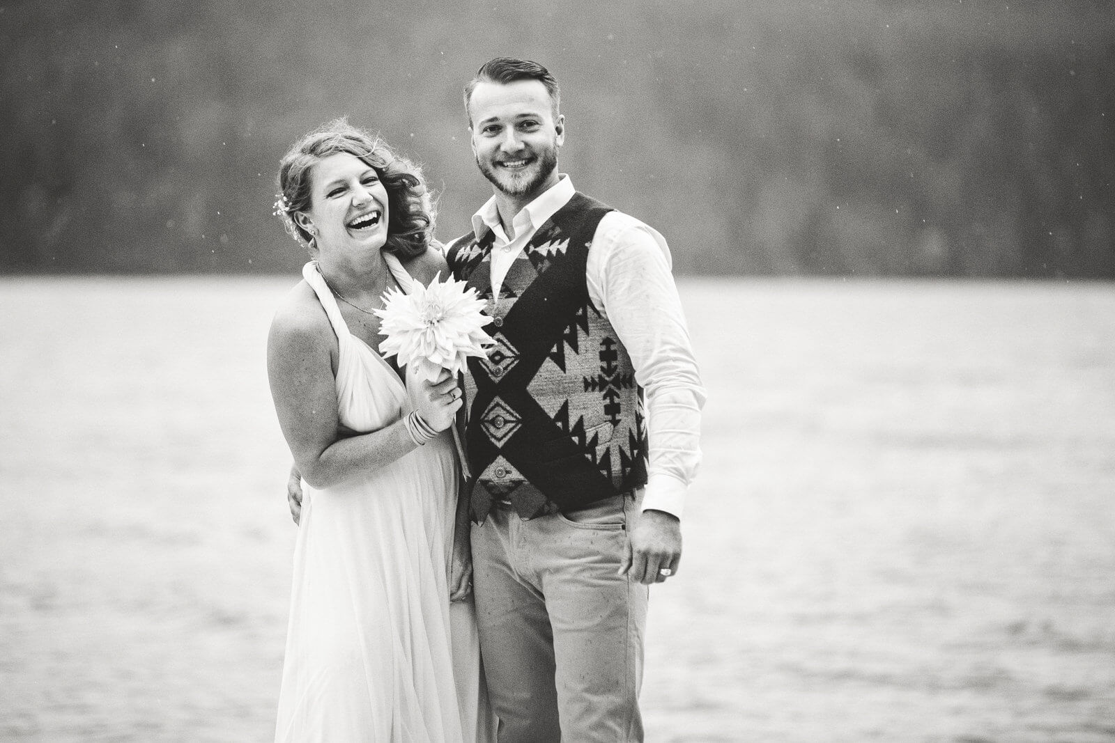 A bride and groom laugh together in the rain at their wedding on Swan Lake in Bigfork Montana