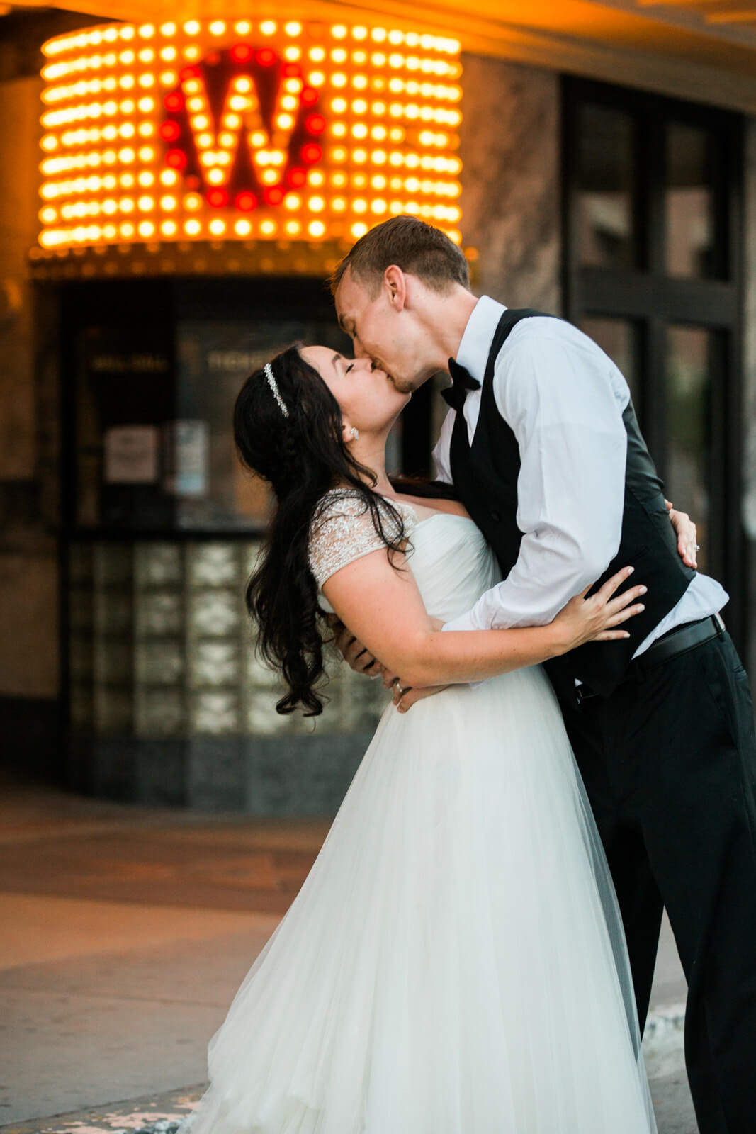 A bride and groom kiss in front of the Wilma Theatre sign in Missoula Montana during their wedding day