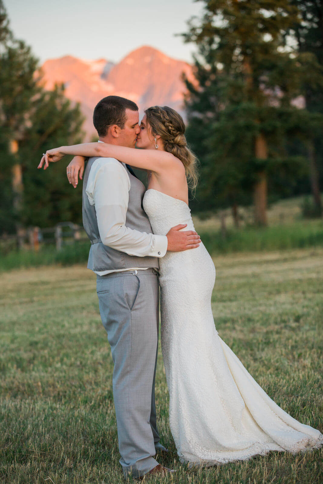A bride and groom kiss in front of the Mission Mountains at their wedding at The Silver Knot in Ronan Montana