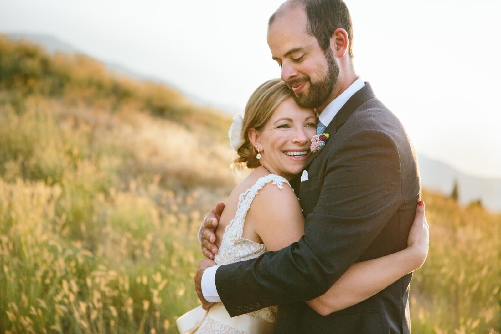 A bride and groom embrace in front of a field of grass at their wedding at the Barn on Mullan in Missoula Montana