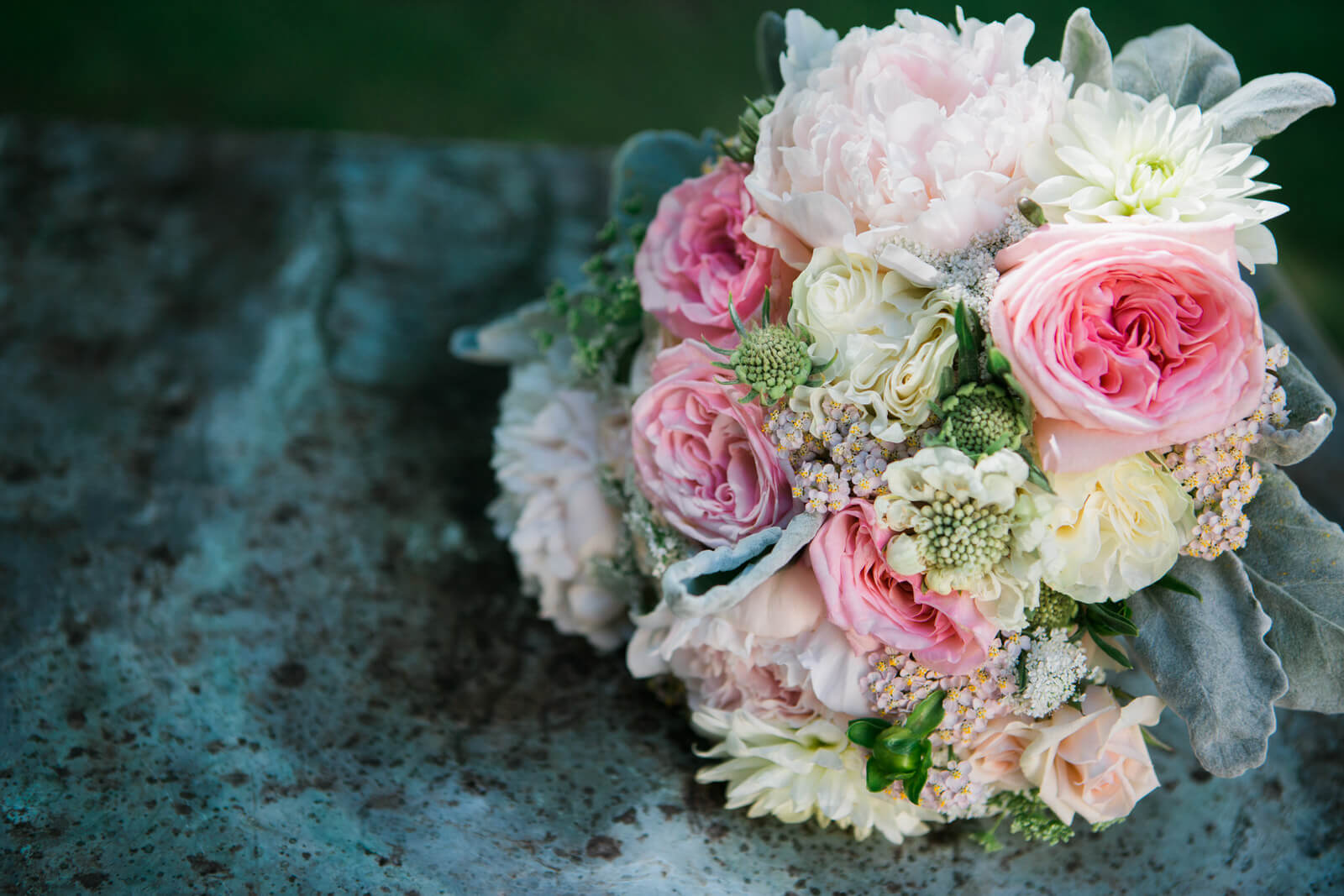 A pastel pink bouquet rests on lichen covered stonework at the Daly Manson in Hamilton Montana during a wedding