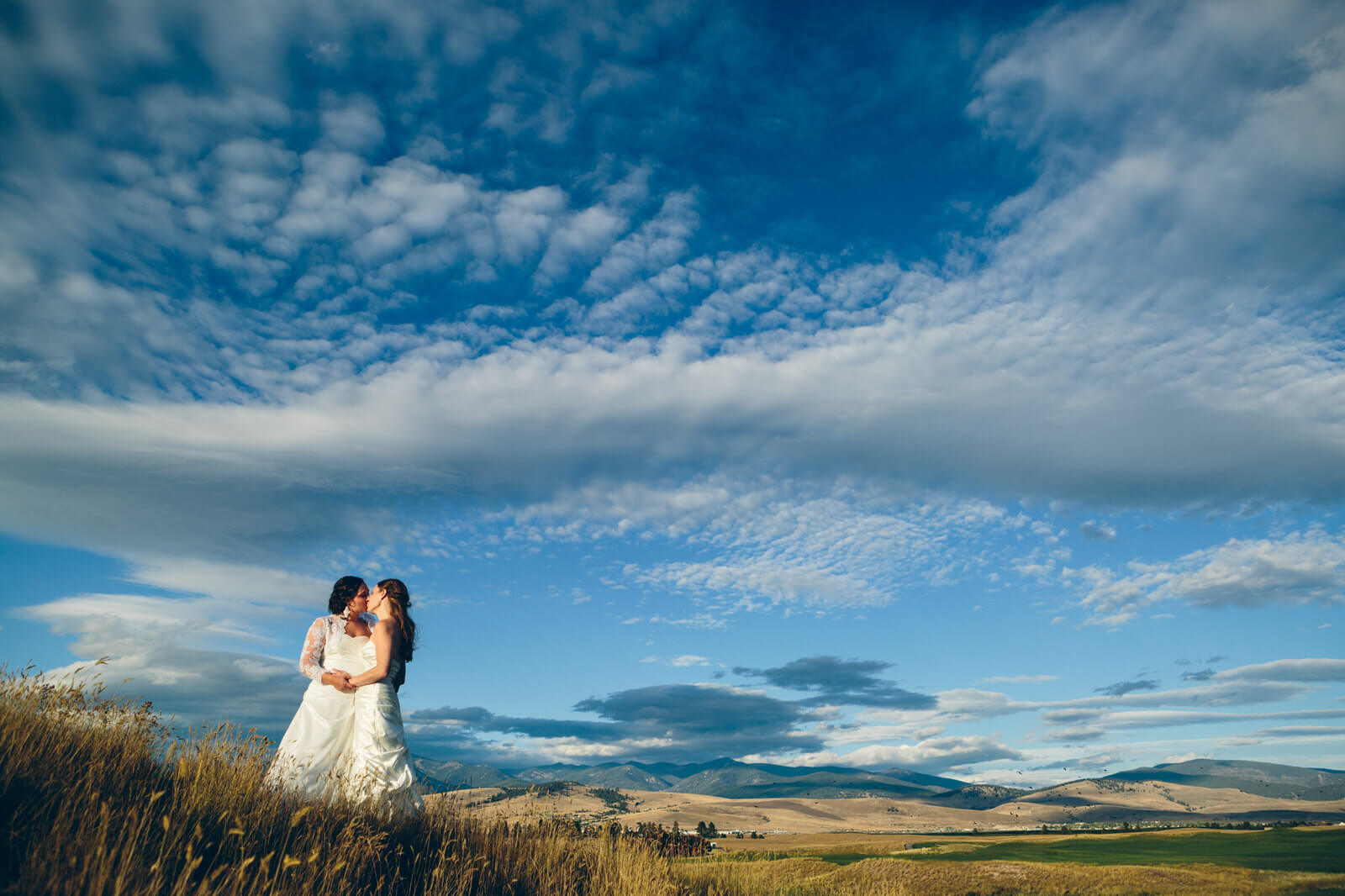 Two brides kiss on a hillside during their wedding at the Barn on Mullan in Missoula Montana