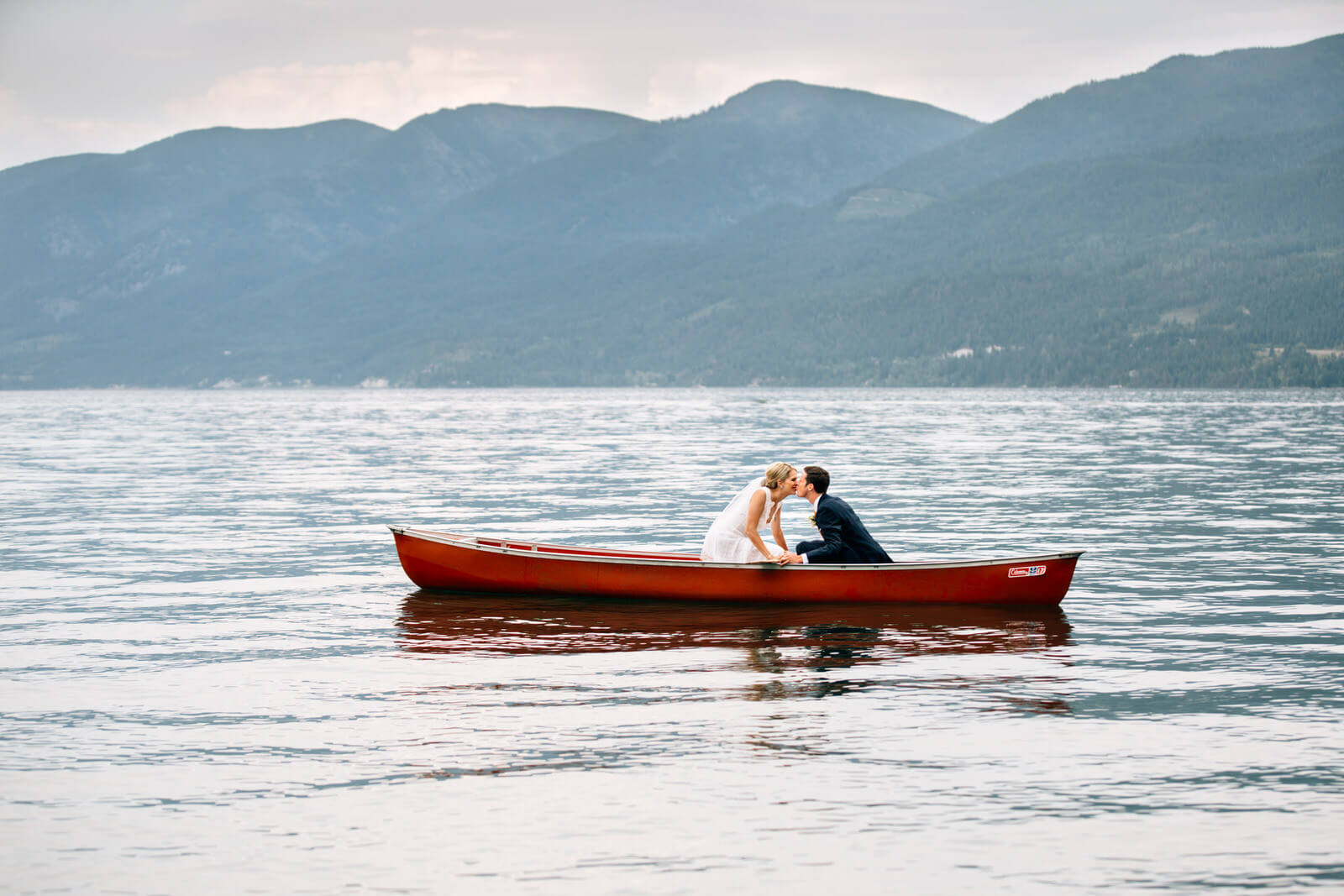 A bride and groom kiss in a canoe on Flathead Lake during their wedding at the Barn at Finley Point in Polson Montana