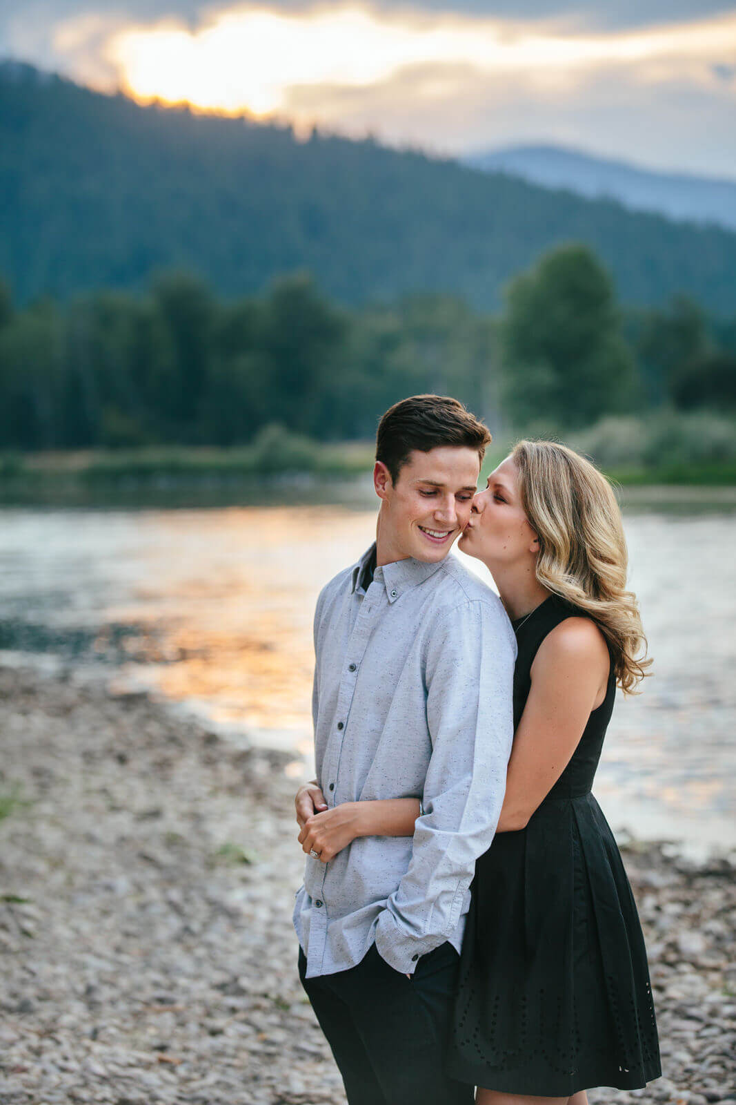 A woman kisses her fiance in front of a river in Missoula Montana during their engagement session