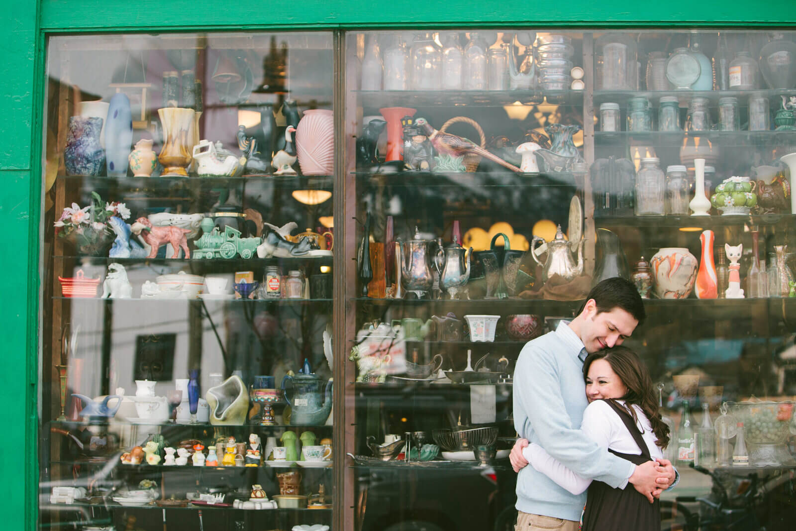 A couple embraces in front of an antique store in Missoula Montana during their engagement photos