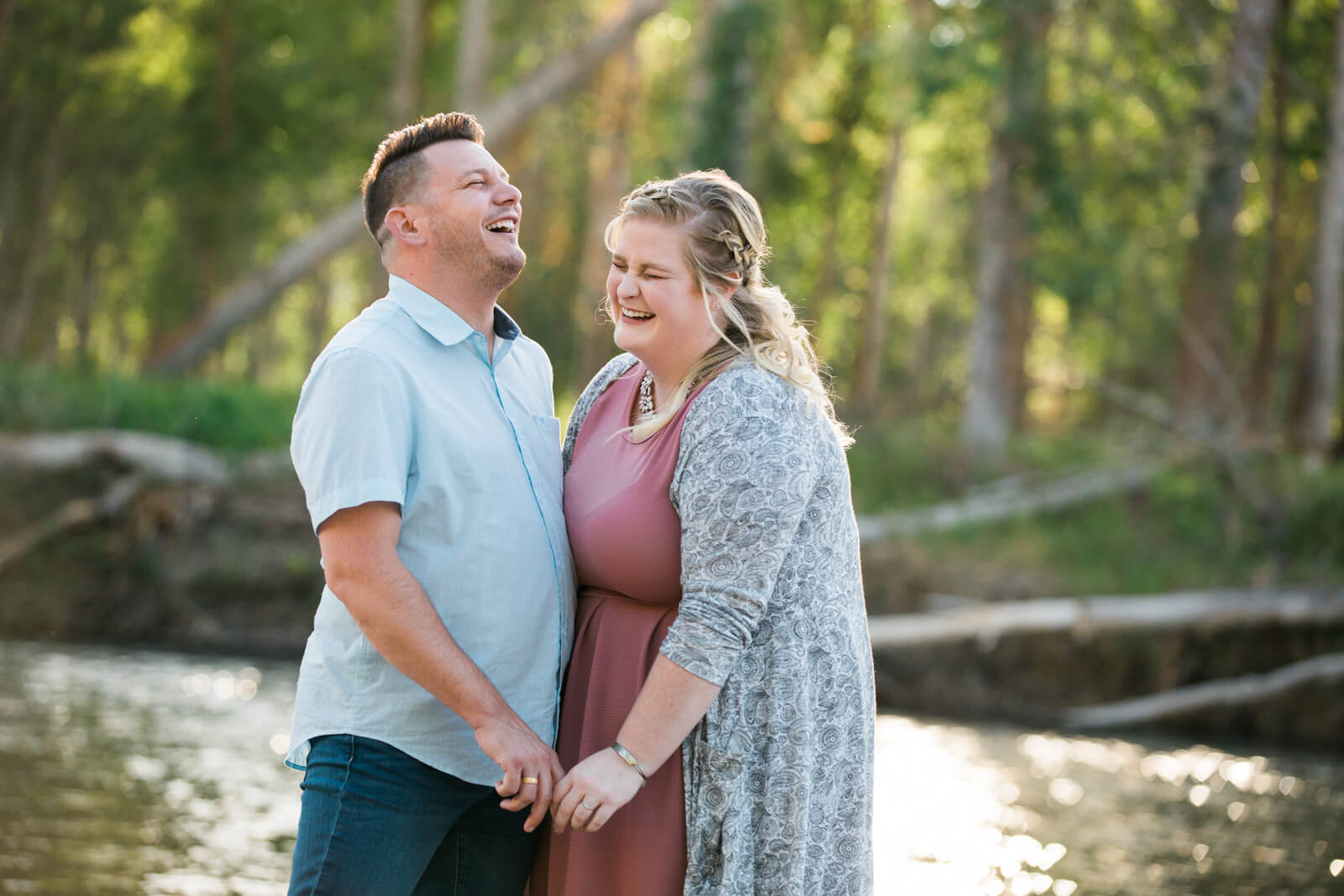 An engaged couple laugh together by a river in Missoula Montana