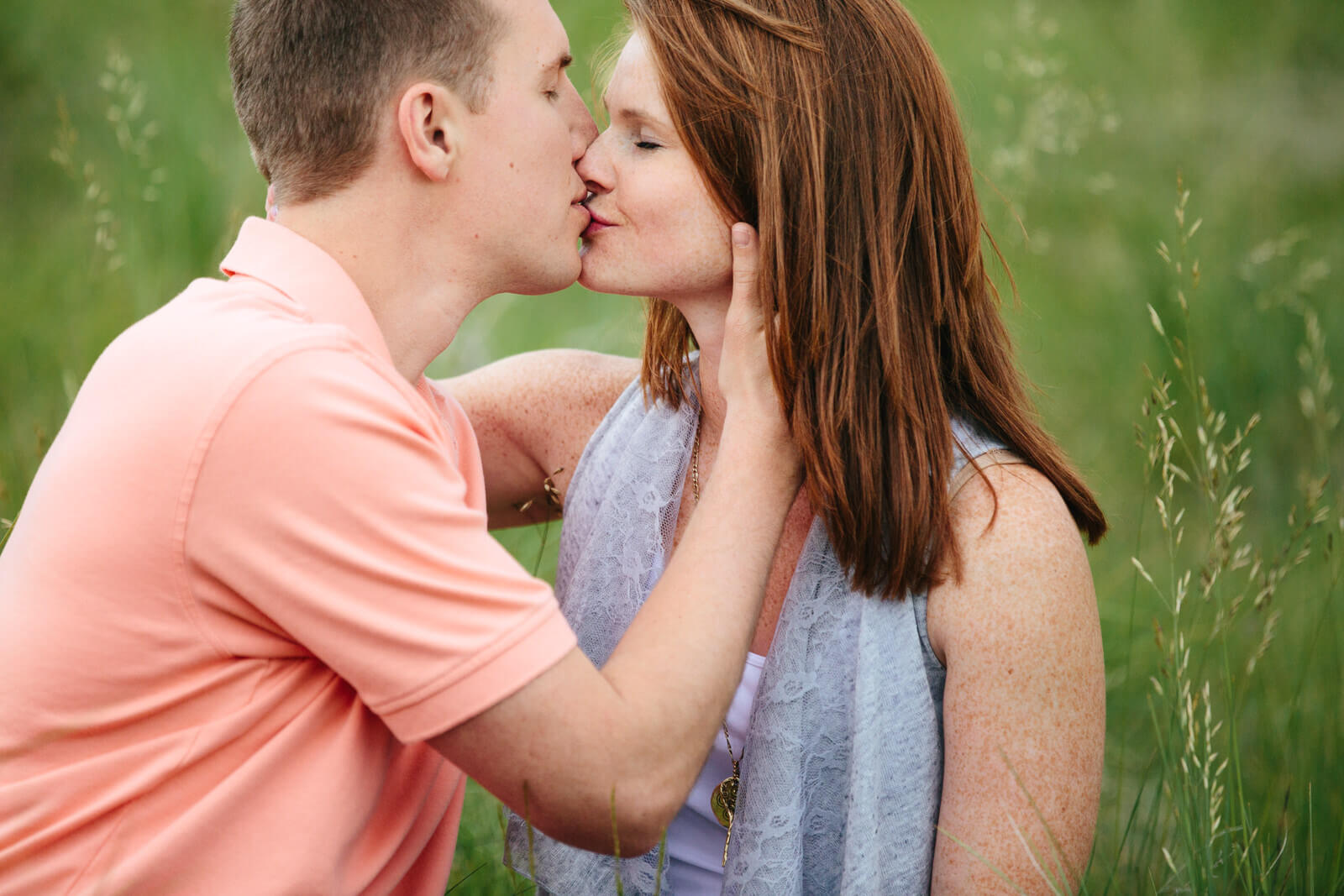 A couple kisses in tall grass during their engagement session in Missoula Montana