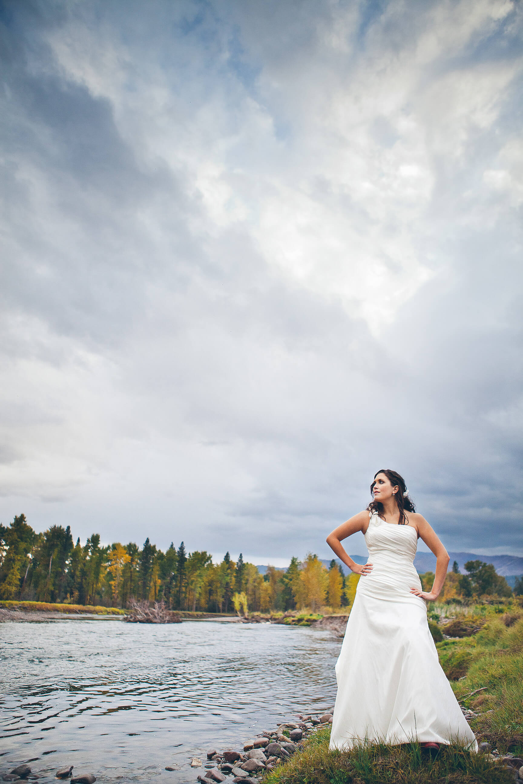 A bride stands near a river in Missoula Montana during her rock the dress photos