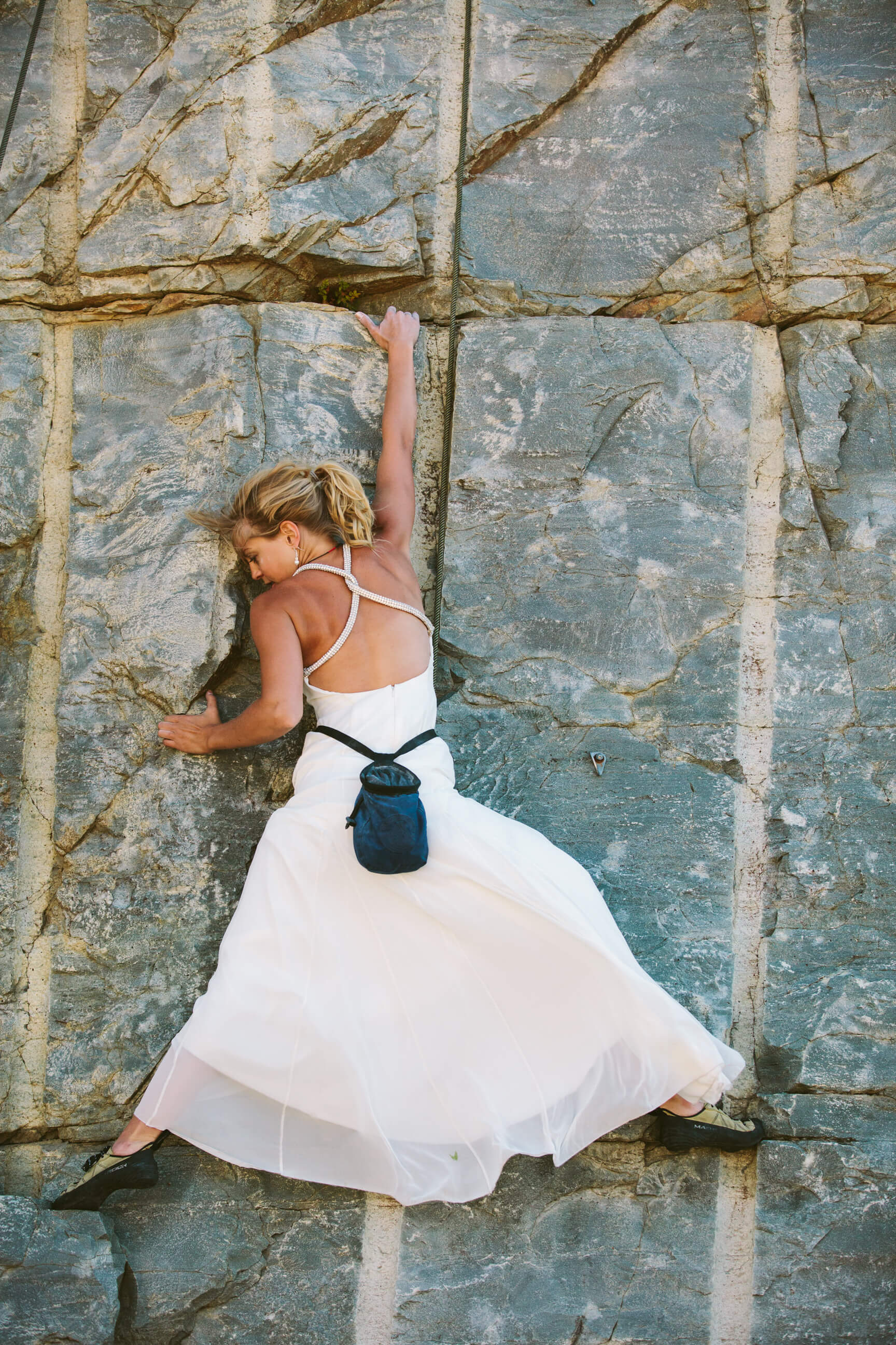 A bride rock climbs in her wedding dress during her rock the dress photos near Lake Koocanusa in Montana