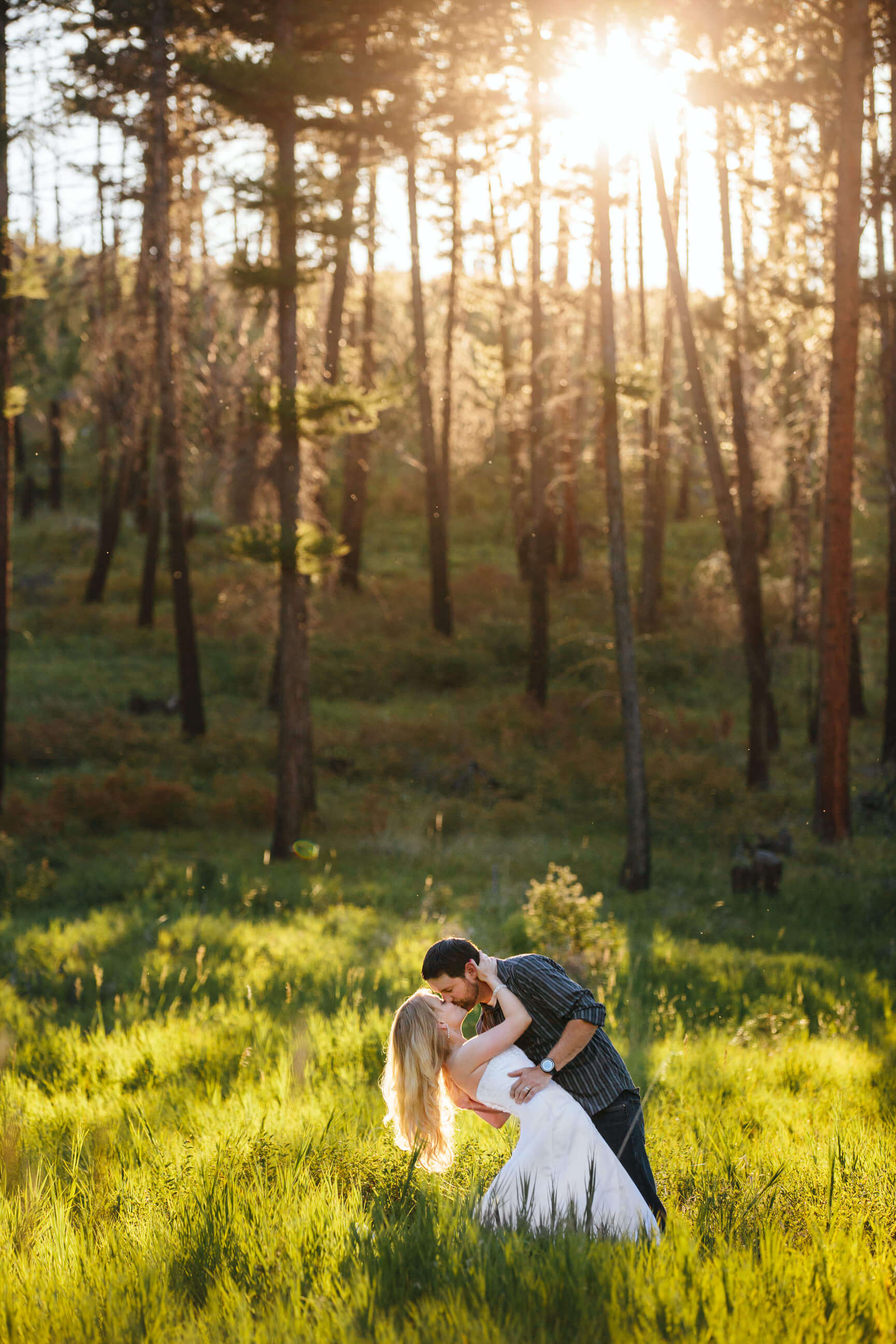 A husband and wife kiss in tall grass during their anniversary rock the dress photos in Missoula Montana