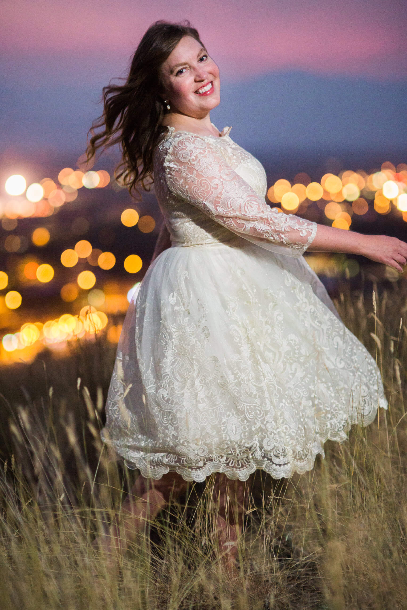 A new bride spins in her dress on a hillside overlooking downtown Missoula at night during her rock the dress photos in Missoula Montana