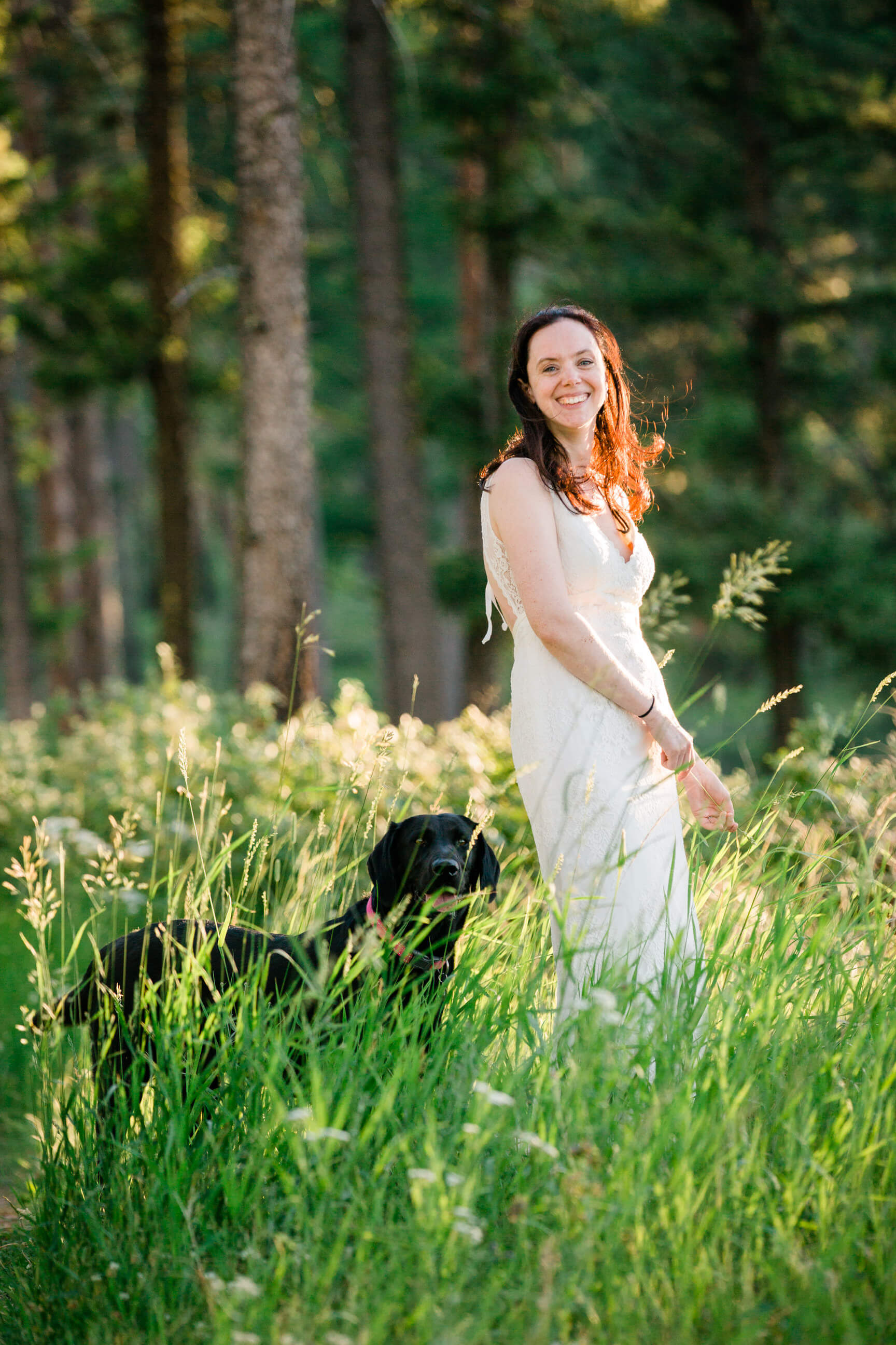 A bride twirls in tall grass alongside her black lab dog during her rock the dress photos in Missoula Montana