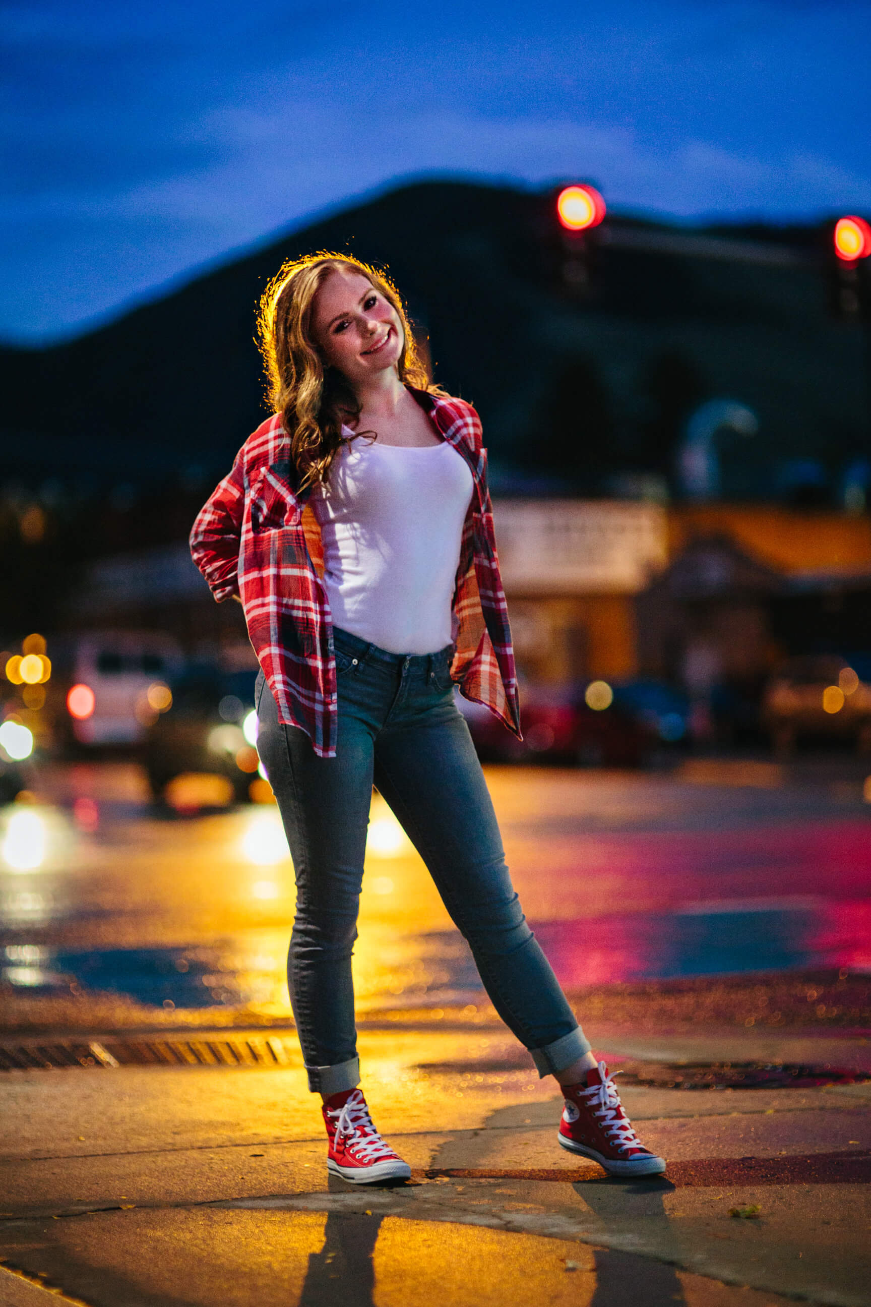 A senior girl smiles as she stands on wet pavement in downtown Missoula during her senior photos