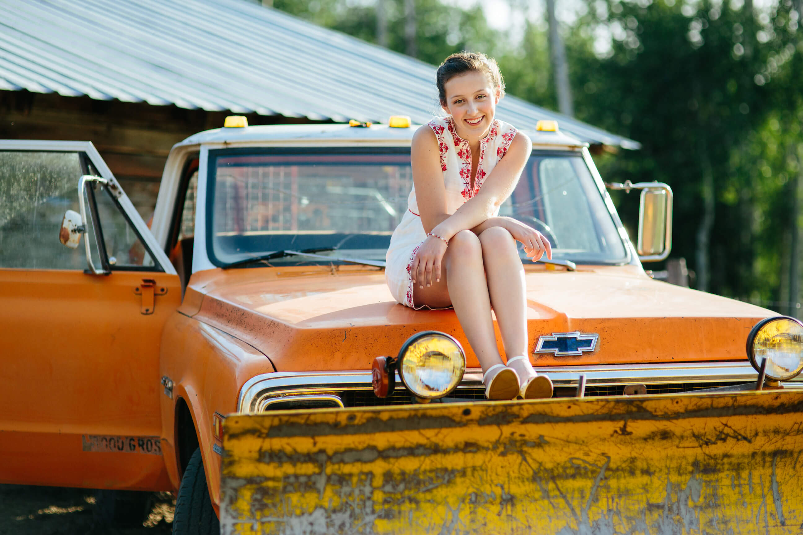 A senior girl sits on top of an old truck during her senior portrait session in Seeley Lake Montana