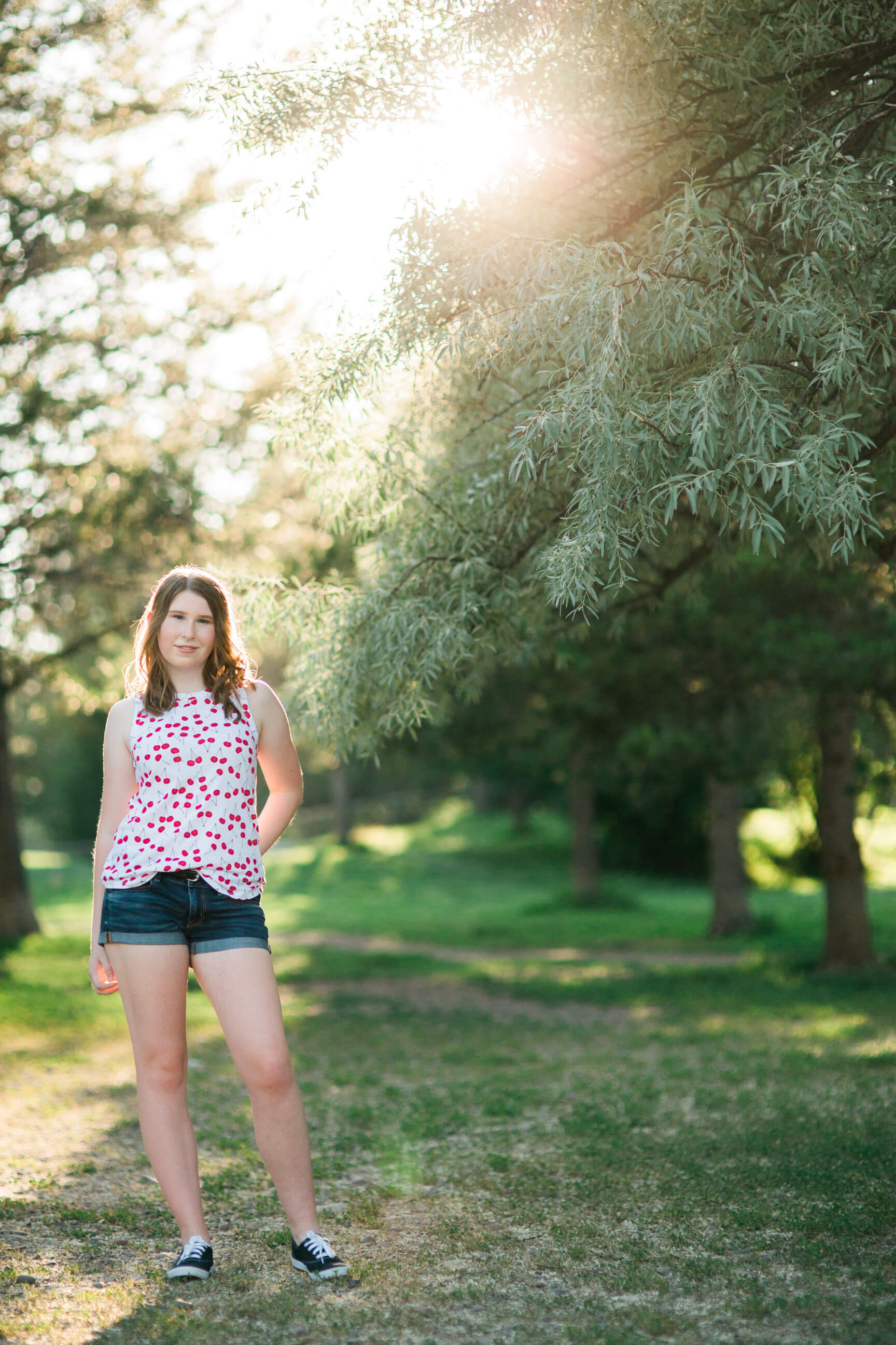 A senior girl poses near a willow tree during her senior photos in Missoula Montana