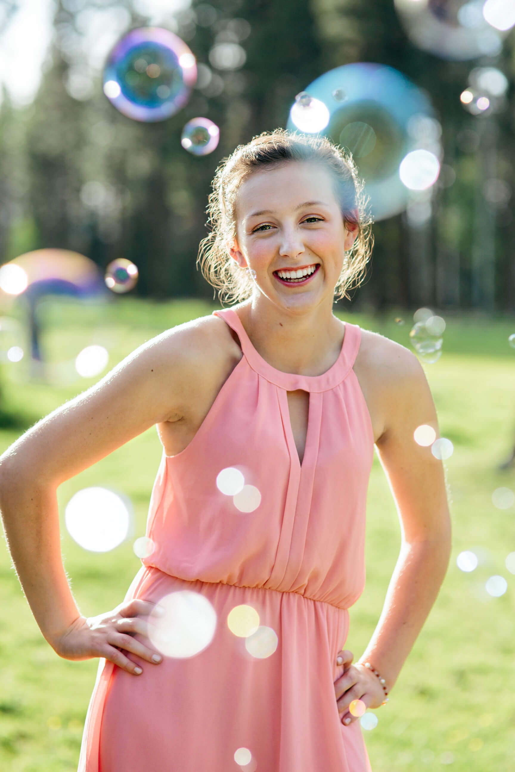 A senior girl laughs through a cloud of bubbles during her senior portraits in Seeley Lake Montana