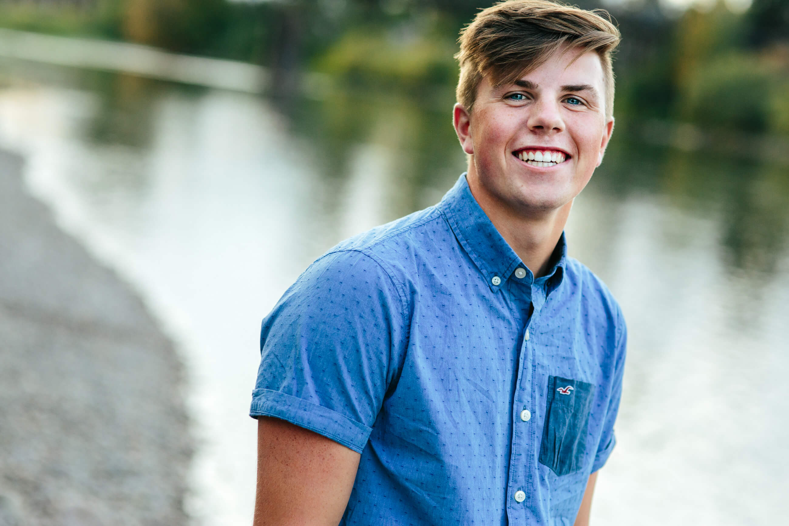 A senior boy smiles during his senior photos in Missoula Montana near the Clark Fork River