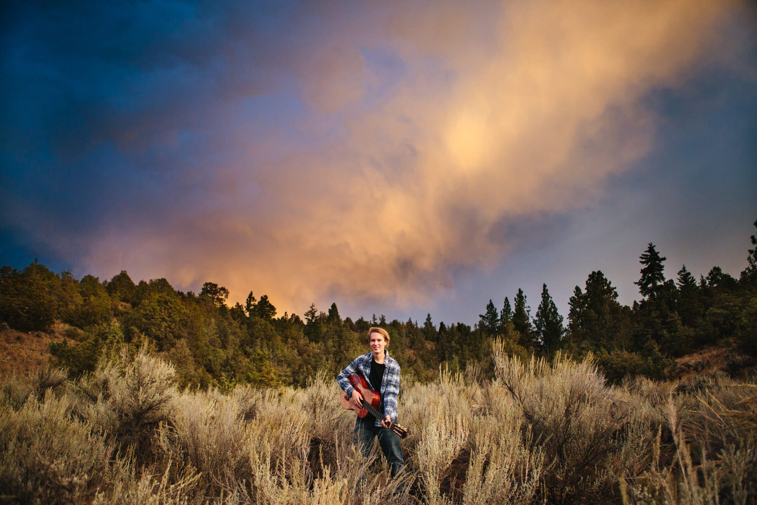 A senior boy plays his guitar during sunset at his Corvallis Montana senior photos