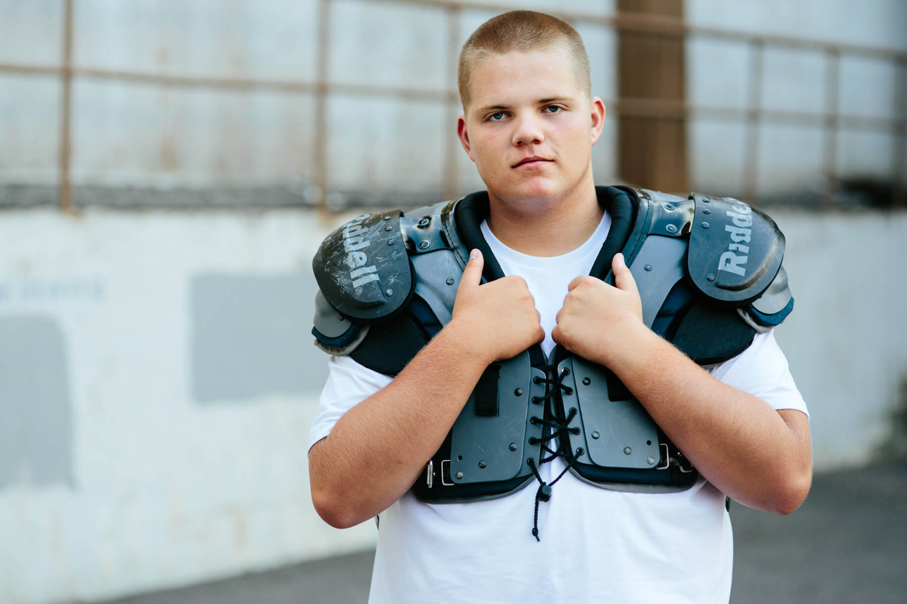 A high school senior boy wears football pads during his senior photos in Missoula Montana