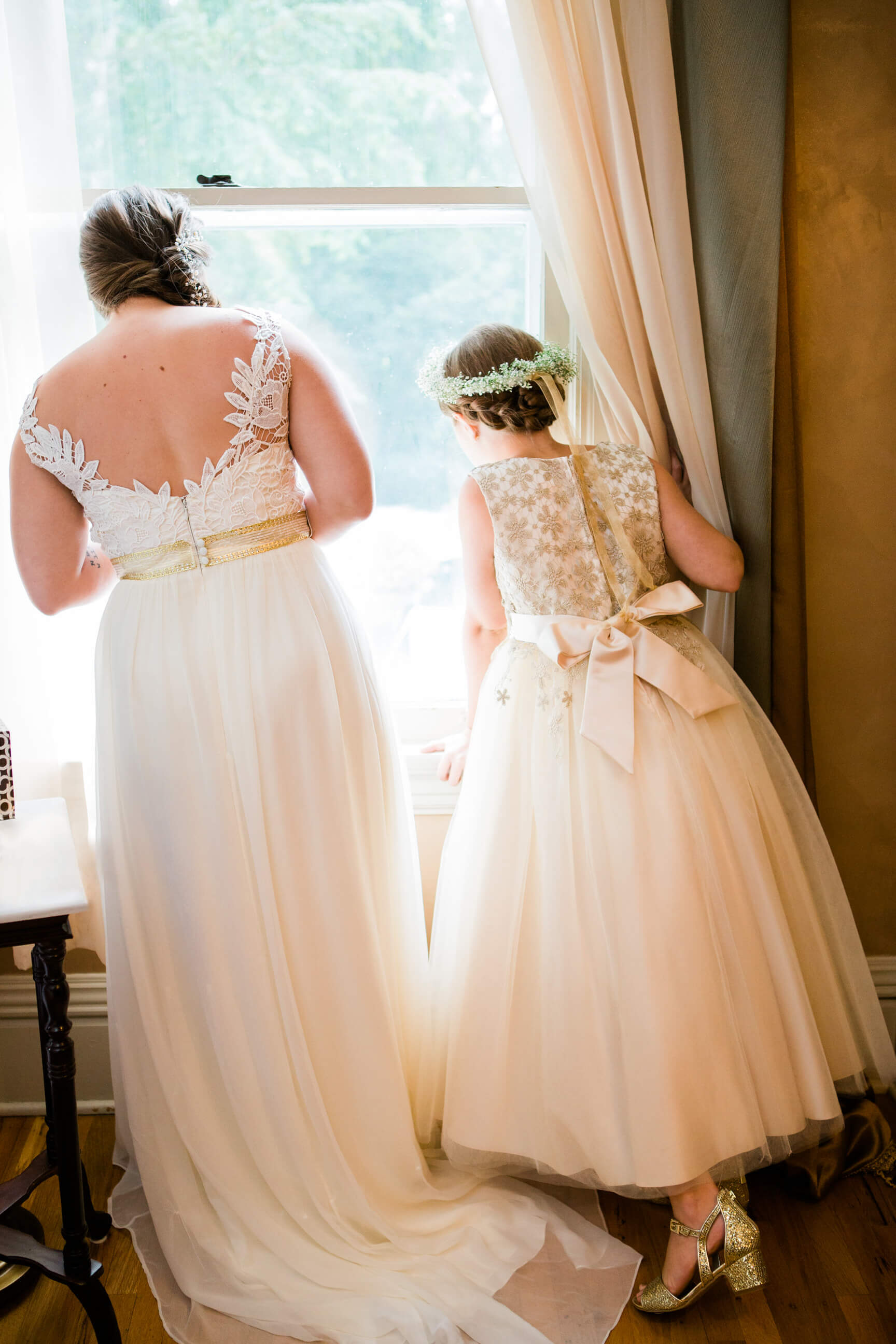 A bride and a flower girl look out the window as they wait for her wedding to start in Missoula Montana