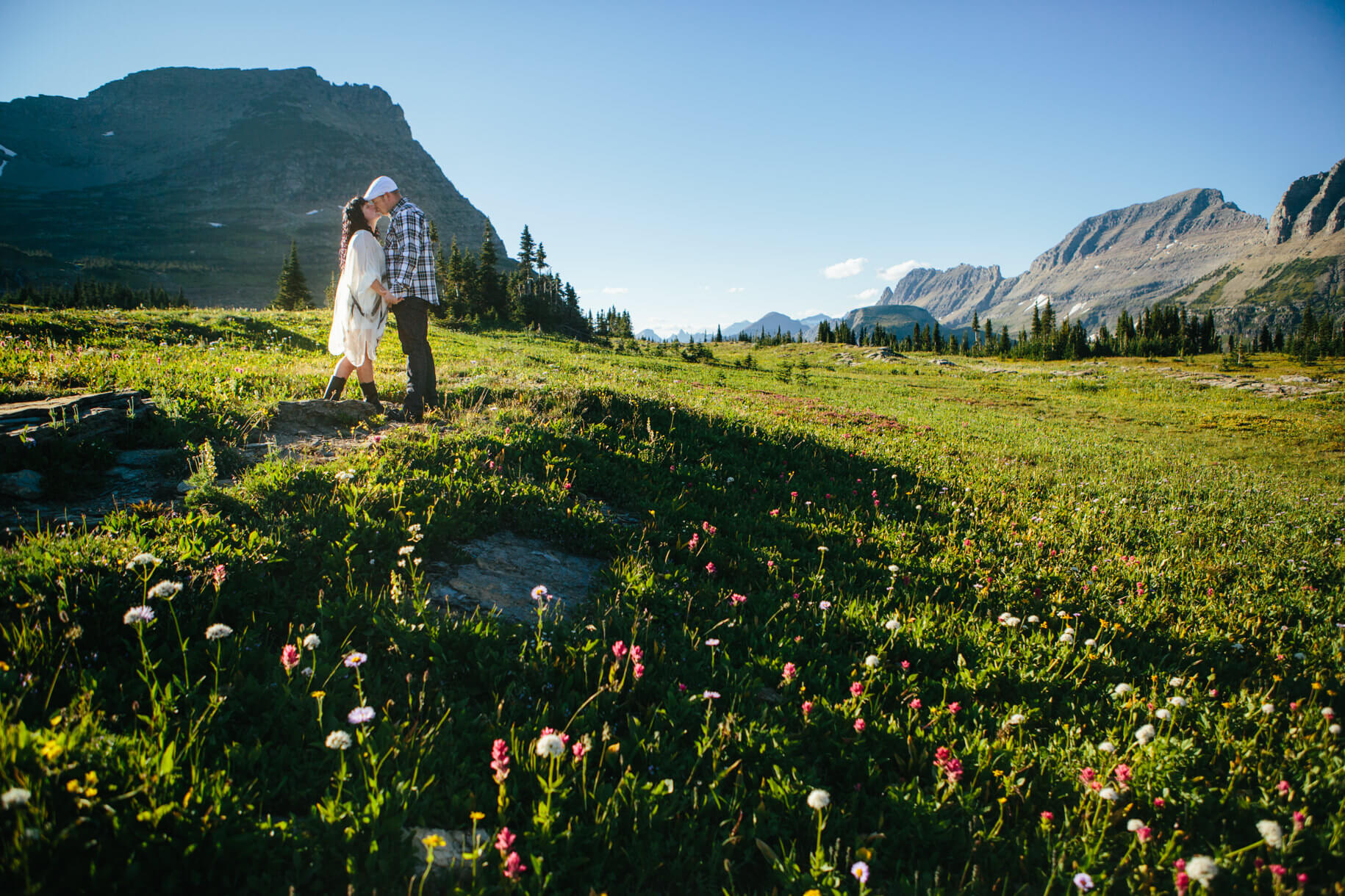 A bride and groom kiss amongst a field of wildflowers at their Glacier National Park elopement in Montana