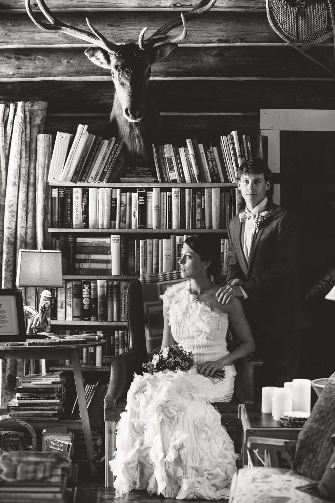 A bride and groom pose among a wall of books during their elopement in Philipsburg Montana