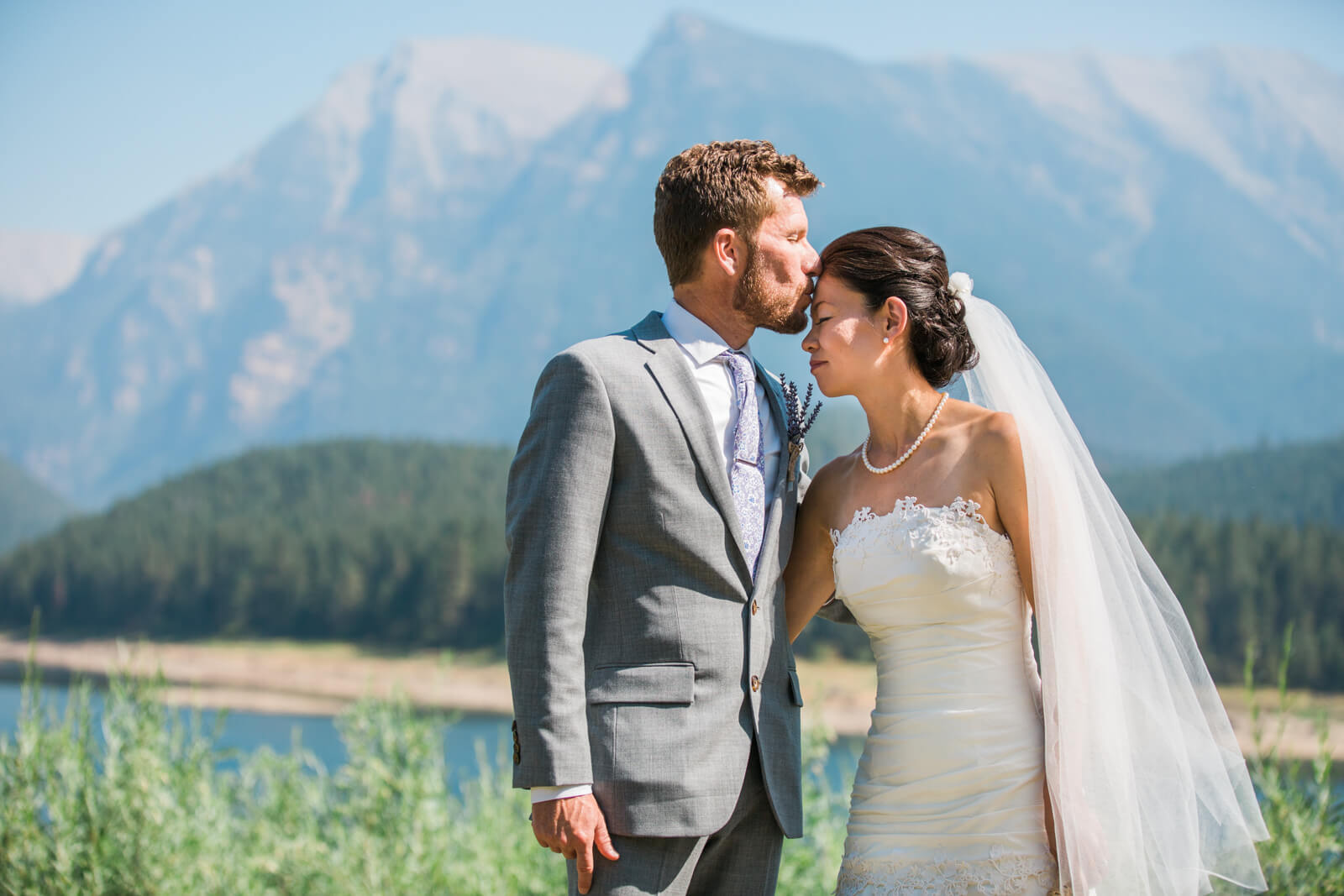 A groom kisses his bride's forehead at their intimate wedding in St Ignatius Montana